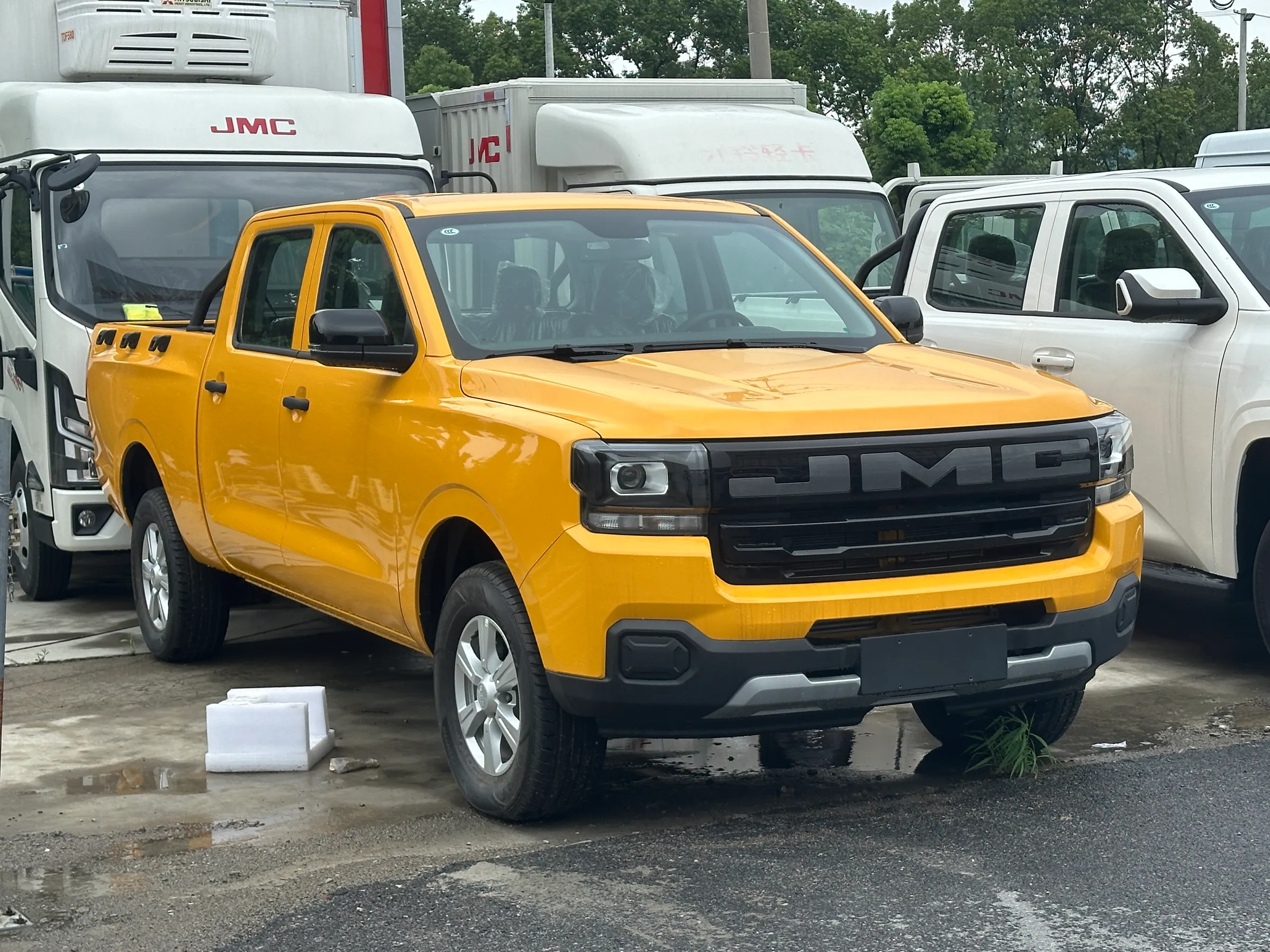 Pick-up JMC Baodian jaune sur un parc de véhicules utilitaires